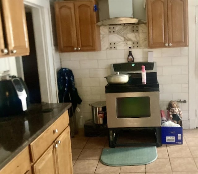 kitchen featuring exhaust hood, light tile patterned floors, and electric stove