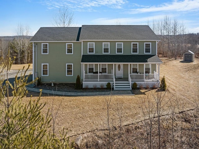 colonial inspired home with a porch, an outbuilding, and a shingled roof