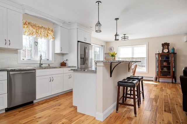 kitchen featuring light wood finished floors, appliances with stainless steel finishes, a breakfast bar, and a sink