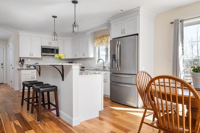 kitchen with backsplash, light wood-type flooring, appliances with stainless steel finishes, and a center island