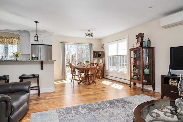 dining space featuring a baseboard heating unit, baseboards, light wood-style flooring, and a wall unit AC