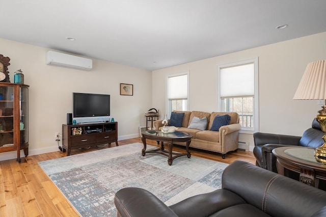 living area with baseboard heating, light wood-style flooring, baseboards, and a wall mounted air conditioner