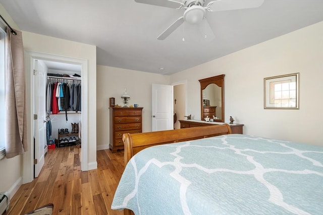 bedroom with light wood-type flooring, a walk in closet, a ceiling fan, a closet, and a baseboard radiator