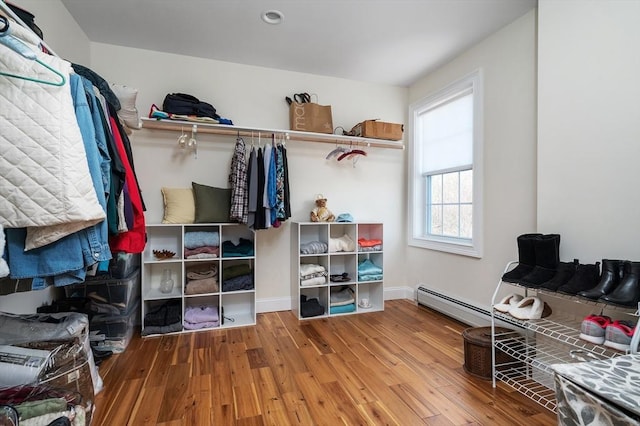 walk in closet featuring a baseboard heating unit and wood finished floors