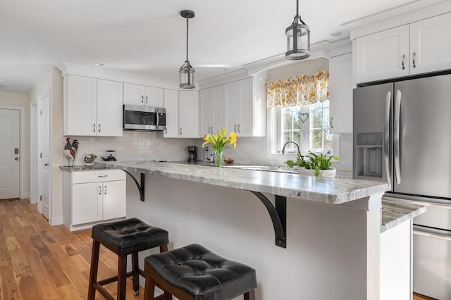 kitchen featuring decorative backsplash, a breakfast bar area, appliances with stainless steel finishes, and white cabinetry