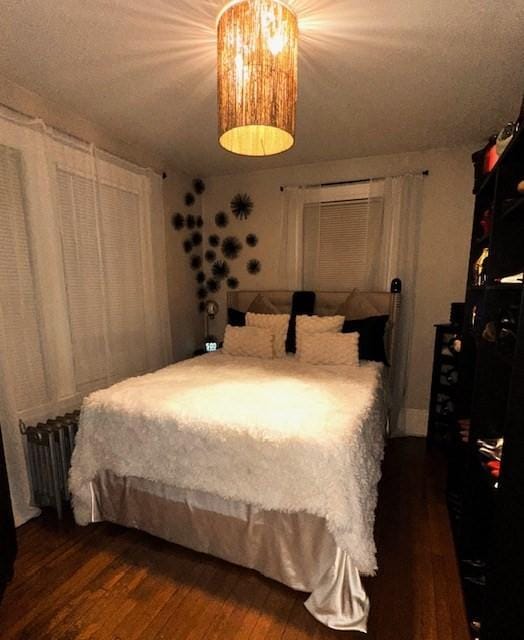 bedroom featuring radiator heating unit and dark wood-type flooring