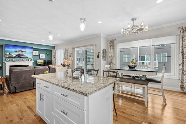 kitchen with white cabinetry, decorative light fixtures, a breakfast bar area, and a kitchen island