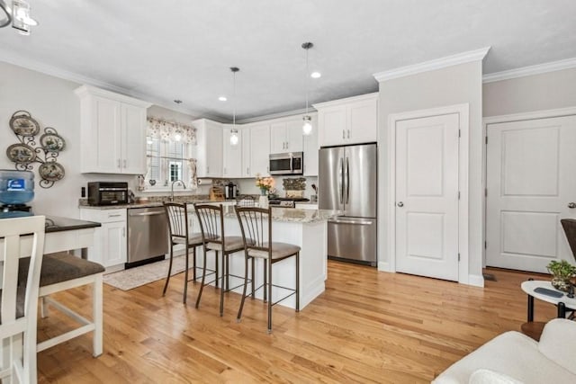 kitchen with stainless steel appliances, white cabinetry, hanging light fixtures, and a center island