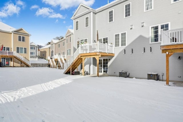 snow covered rear of property with a deck