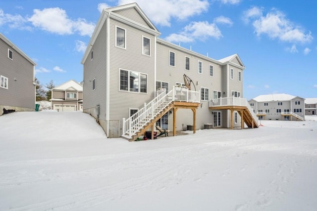 snow covered back of property with a deck