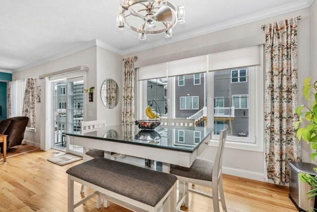 dining area with crown molding, light hardwood / wood-style floors, and a notable chandelier