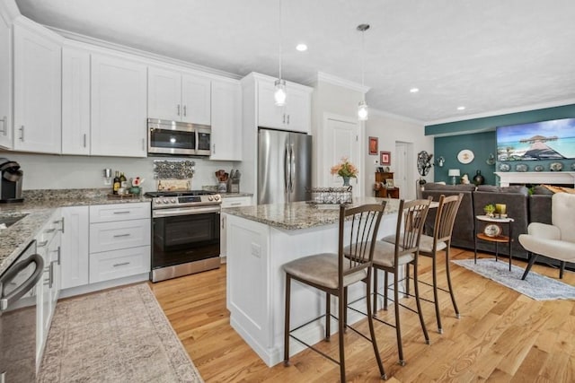 kitchen featuring white cabinetry, hanging light fixtures, stainless steel appliances, and a kitchen island