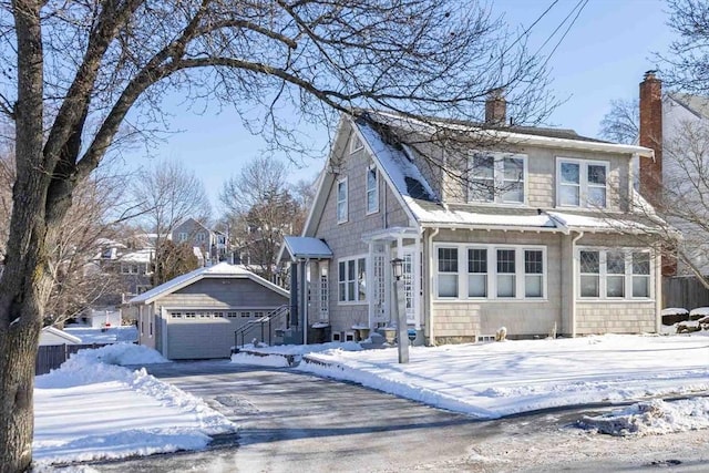 view of front of house with a garage, a chimney, and an outdoor structure