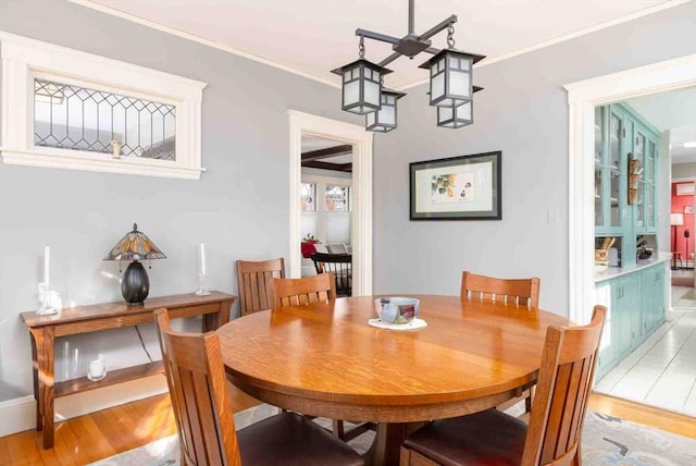 dining space with ornamental molding and light wood-type flooring