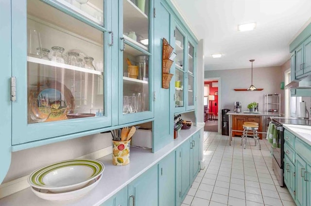 kitchen featuring light tile patterned floors, blue cabinets, electric range, light countertops, and pendant lighting