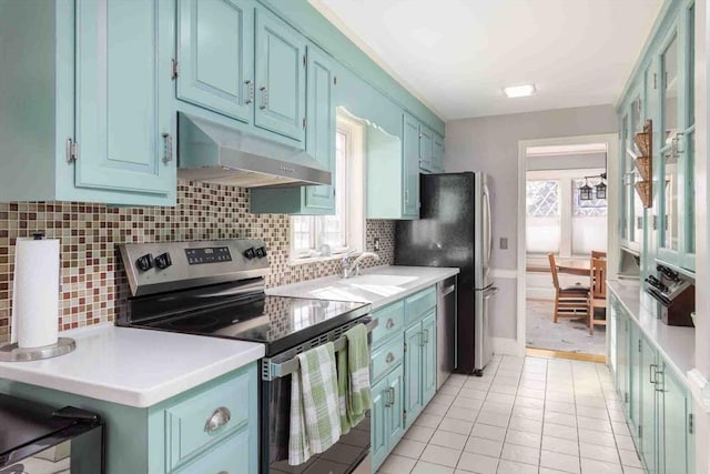 kitchen with under cabinet range hood, blue cabinetry, light countertops, and stainless steel range with electric cooktop