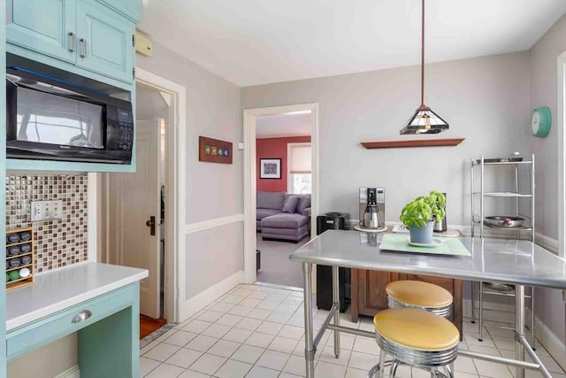 kitchen with black microwave, light tile patterned floors, baseboards, light countertops, and blue cabinetry