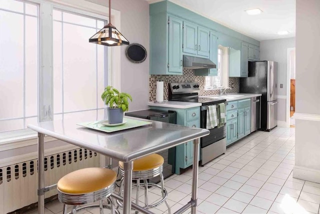 kitchen featuring stainless steel appliances, radiator, decorative backsplash, blue cabinets, and under cabinet range hood