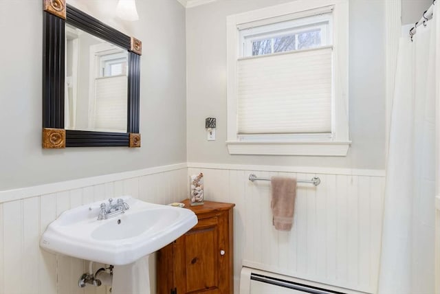 full bathroom with a baseboard heating unit, a wainscoted wall, and a sink