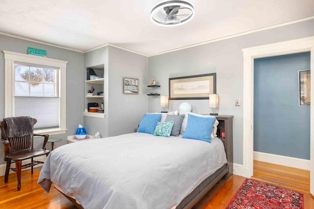 bedroom with ornamental molding, baseboards, and wood finished floors