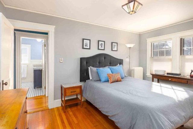 bedroom featuring ornamental molding, radiator heating unit, wood-type flooring, and baseboards