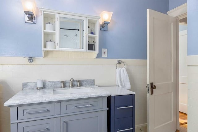 bathroom with a wainscoted wall, tile walls, and vanity