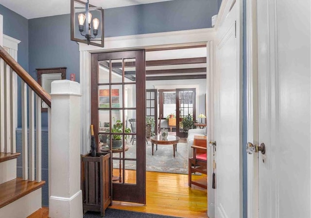 foyer entrance featuring a chandelier, wood finished floors, french doors, and stairs