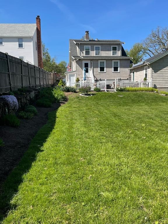 rear view of property with fence and a lawn