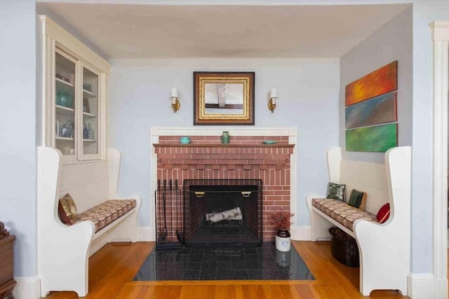 sitting room featuring a brick fireplace and wood finished floors