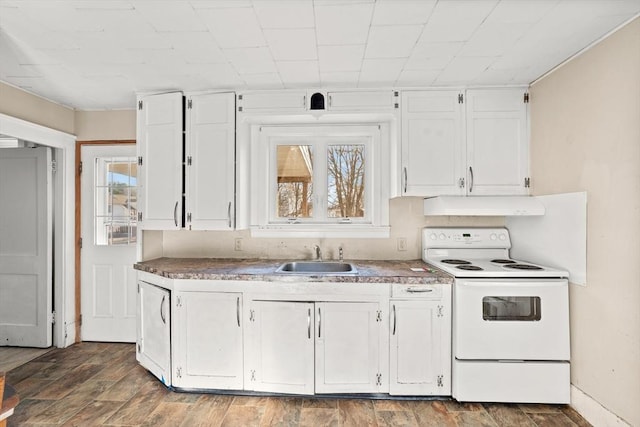 kitchen featuring sink, wood-type flooring, white electric range, washer / clothes dryer, and white cabinetry