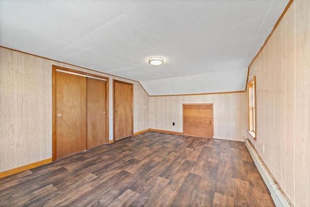 bonus room with wooden walls, dark hardwood / wood-style flooring, a baseboard radiator, and vaulted ceiling