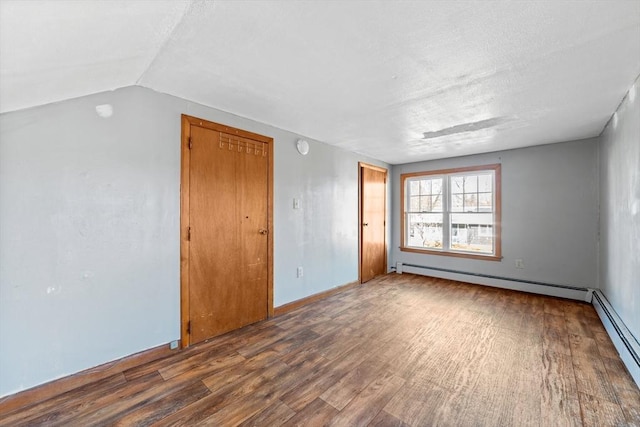 spare room with baseboard heating, a textured ceiling, wood-type flooring, and lofted ceiling