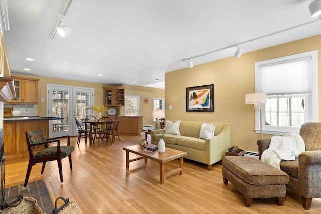 living room with track lighting, french doors, a baseboard radiator, and light wood-type flooring