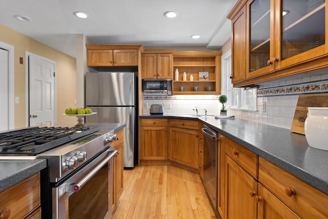 kitchen featuring sink, decorative backsplash, light hardwood / wood-style floors, and appliances with stainless steel finishes