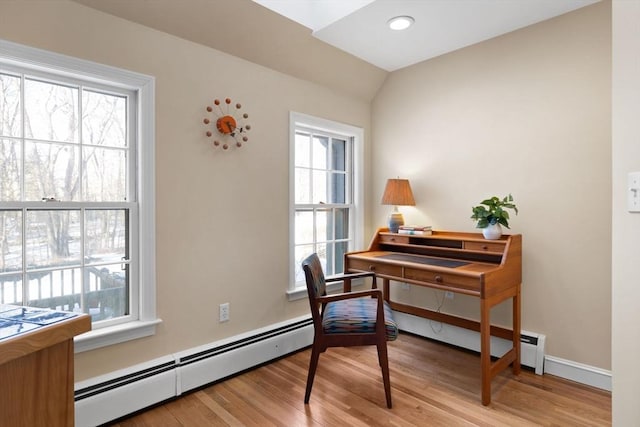 office space featuring baseboard heating, light hardwood / wood-style floors, and a wealth of natural light