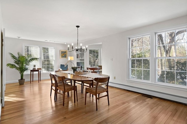 dining space with a baseboard radiator, light hardwood / wood-style flooring, and a notable chandelier