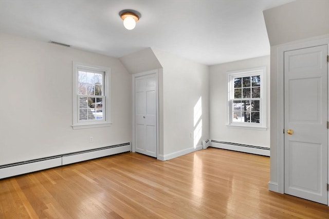 additional living space with light hardwood / wood-style flooring and a baseboard heating unit