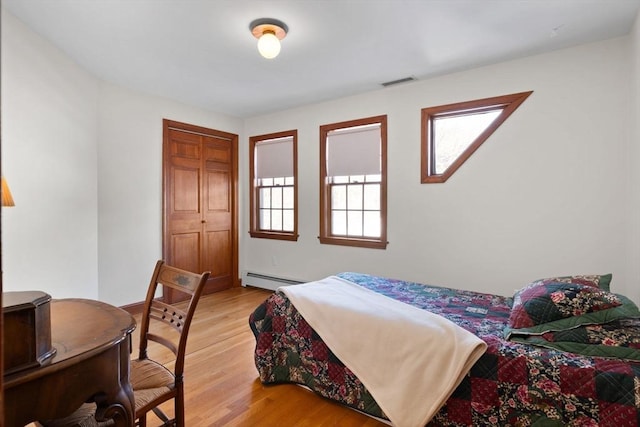 bedroom with a baseboard radiator and light hardwood / wood-style flooring