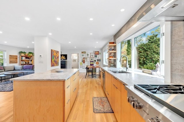kitchen with a kitchen island, recessed lighting, stovetop, a sink, and light wood finished floors