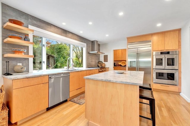 kitchen with light wood-type flooring, a sink, wall chimney exhaust hood, and stainless steel appliances