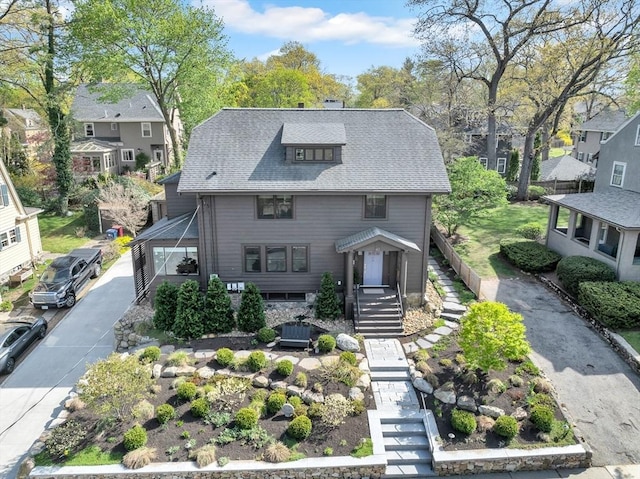 view of front facade with a residential view, a chimney, stairs, and roof with shingles