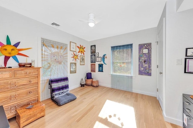 living area with ceiling fan, visible vents, baseboards, and light wood-style floors