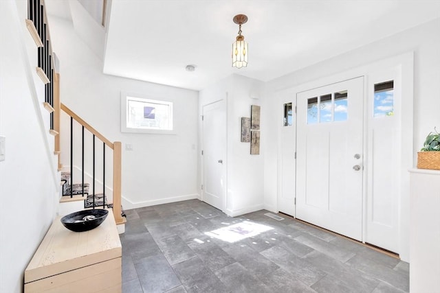 entryway featuring plenty of natural light, stone finish flooring, stairs, and baseboards