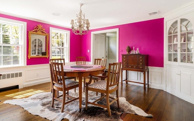 dining room featuring radiator, a chandelier, healthy amount of natural light, wood finished floors, and wainscoting