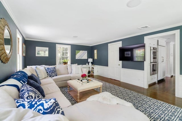living room with wood finished floors, ornamental molding, and a wainscoted wall