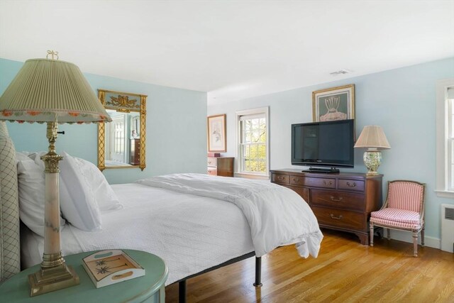 bedroom with light wood-type flooring and radiator heating unit
