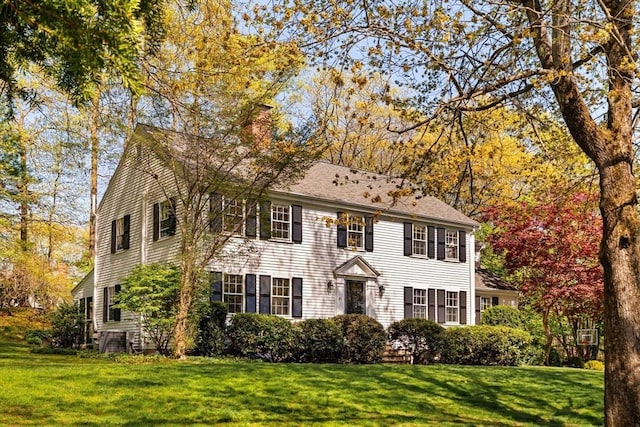 colonial inspired home with a chimney and a front yard