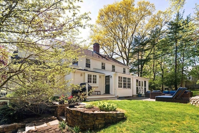 rear view of property featuring an outdoor hangout area, a chimney, a lawn, and a patio