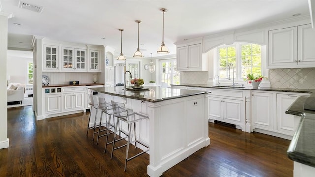 kitchen featuring a sink, white cabinetry, backsplash, dark wood-style flooring, and glass insert cabinets