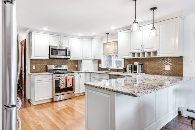 315 Pleasant St, Chatham, MA 02659 - kitchen with appliances with stainless steel finishes, a peninsula, a sink, light stone counters, and white cabinets